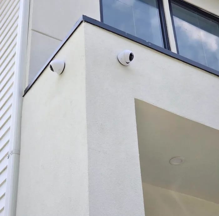 Two dome security cameras cleanly mounted on the corner of a modern stucco building by HD Installs.