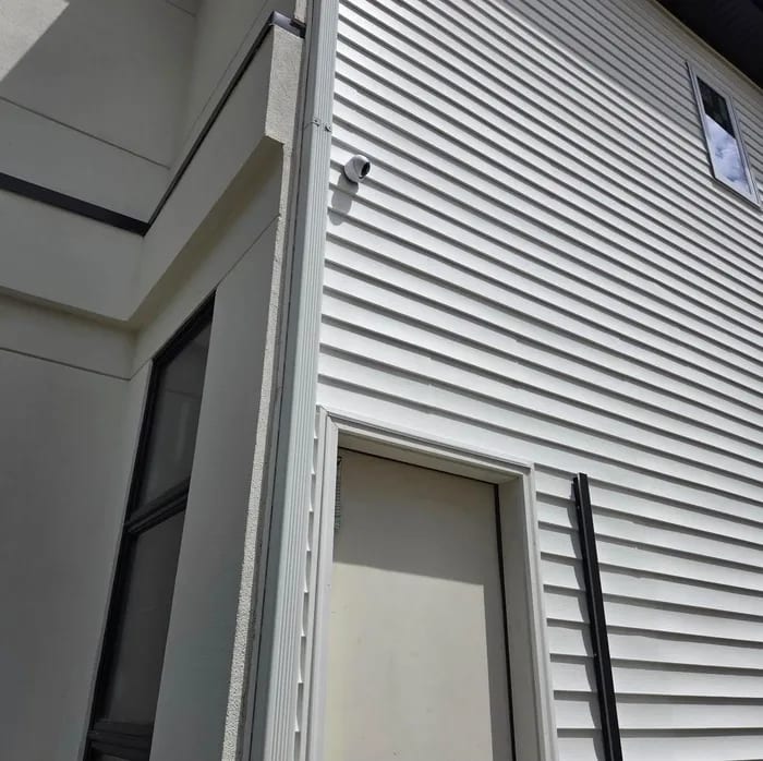 A video doorbell installed cleanly on a stone entry pillar by HD Installs, in daylight.